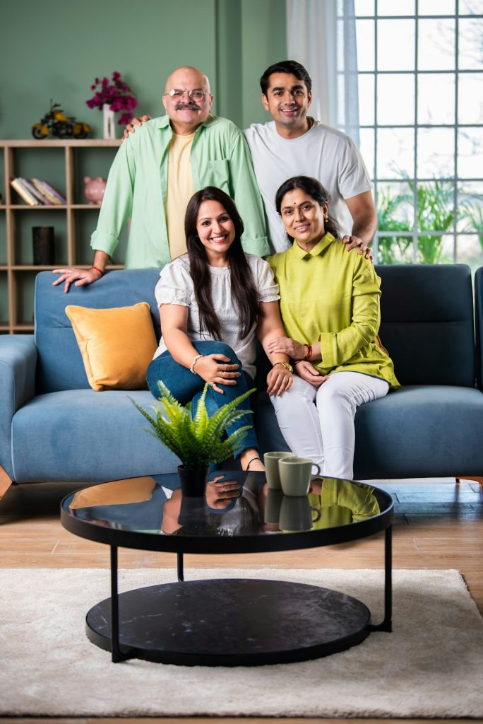 Portrait of happy Indian family of four sitting in modern living room